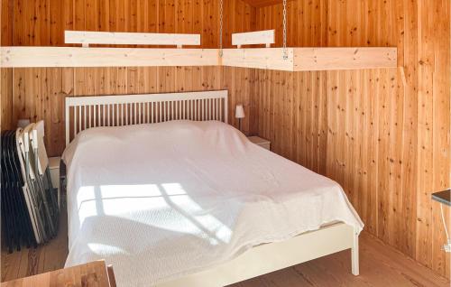 1 dormitorio con 1 cama blanca en una pared de madera en Stunning Home In Ljugarn With Outdoor Swimming Pool en Ljugarn