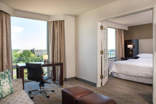 a hotel room with a bed and a desk and a window at Sheraton Suites Chicago Elk Grove in Elk Grove Village