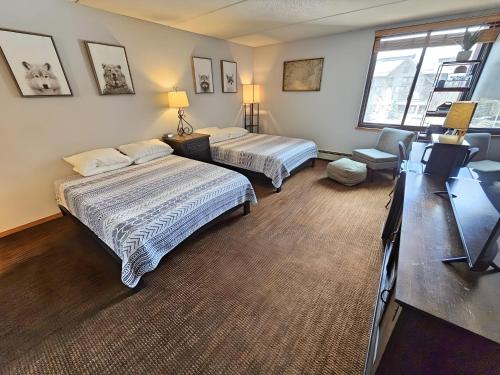 a bedroom with two beds and a desk and a window at Village square 442 Center Village Copper Mountain in Copper Mountain