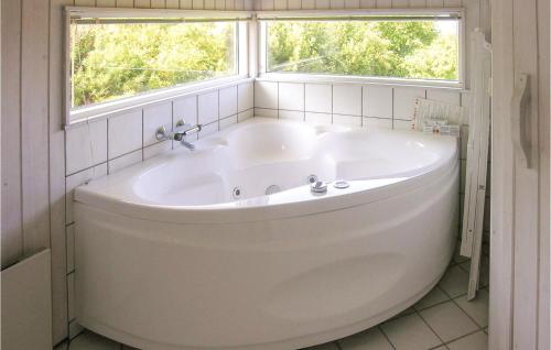 - Baño con bañera blanca y 2 ventanas en Gorgeous Home In Asperup With Sauna, en Asperup