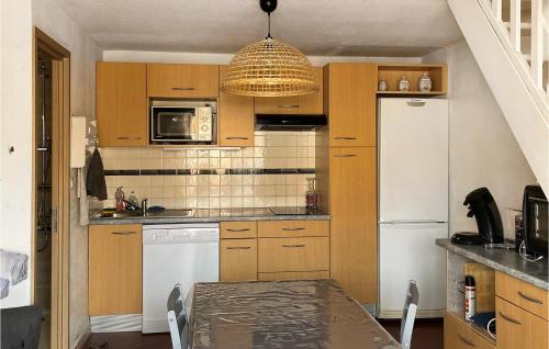 uma cozinha com armários de madeira e um frigorífico branco em Beautiful Home In Saint Pierre La Mer With Kitchen em Saint Pierre La Mer