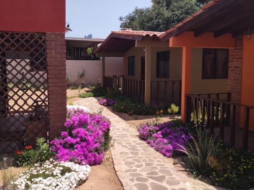 un jardín con flores púrpuras y blancas junto a una casa en Villas Rincón del Paraíso, en Las Palmas