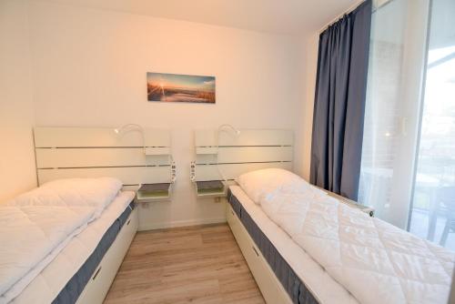 2 camas en una habitación con ventana en Haus "Hohe Worth" Appartement HW103, en Duhnen