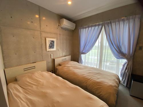 宜野座的住宿－Ｂ＆ＢTandem，一间卧室设有两张床和窗户。