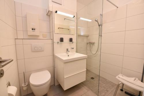 y baño con aseo, lavabo y ducha. en Haus "Luv und Lee" Appartement LUV25, en Döse