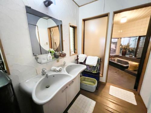 a bathroom with a sink and a mirror and a tub at 貸別荘・グランピングひめしゃら in Kirishima