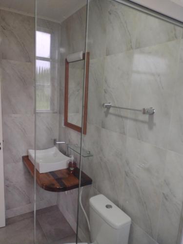 a bathroom with a shower and a toilet and a sink at Pousada das Palmeiras in Pelotas