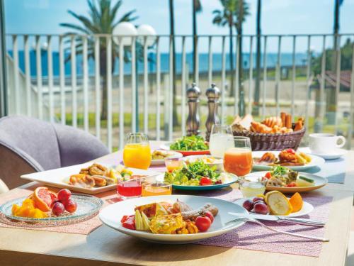 a table with plates of food on a table with the beach at Tokyo Bay Tokyu Hotel in Urayasu