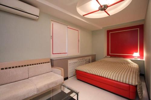 una camera con letto, divano e ventilatore a soffitto di HOTEL Iz bayside 大人専用 a Funabashi