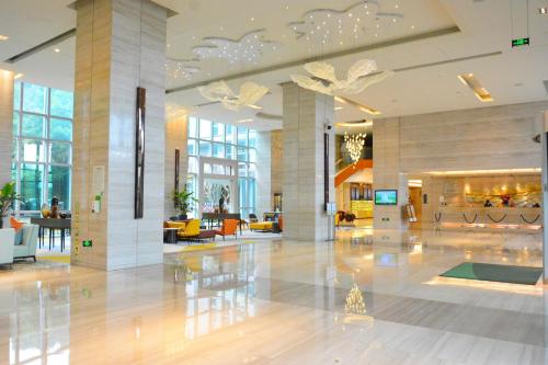 a lobby of a building with tables and chairs at Junluxe Hotel Guangzhou Science City-Free Shuttle Bus Service to Guangzhou Canton Fair in Guangzhou