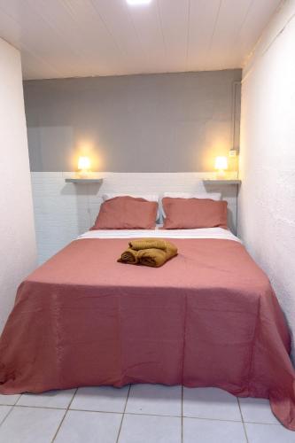 a bedroom with a large bed with a red blanket at Noronha Economy Suítes - Hospedagem com melhor localização e custo benefício da ilha in Fernando de Noronha