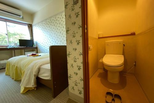 a bathroom with a bed and a toilet in a room at Tango Onsen Hashiudosou in Kyotango