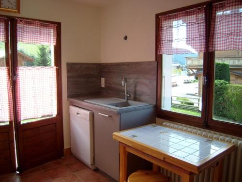 a kitchen with a sink and a refrigerator and windows at Chalet Crest-Voland, 6 pièces, 8 personnes - FR-1-733-2 in Crest-Voland