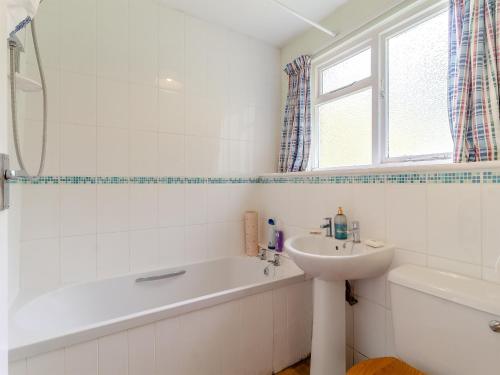 a white bathroom with a sink and a tub and a sink at Oaklawn Cottage in Eye