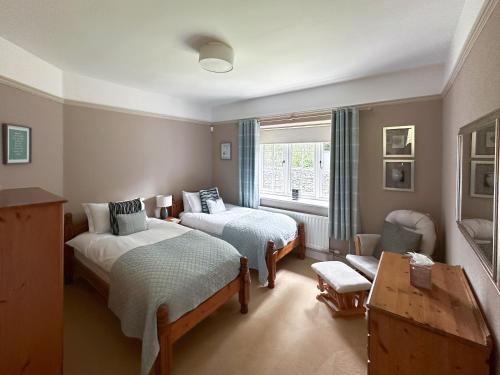 a bedroom with two beds and a chair and a window at Granton Lodge in Far Sawrey