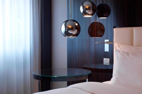 a bedroom with a bed and a table and lights at Le Méridien Etoile in Paris