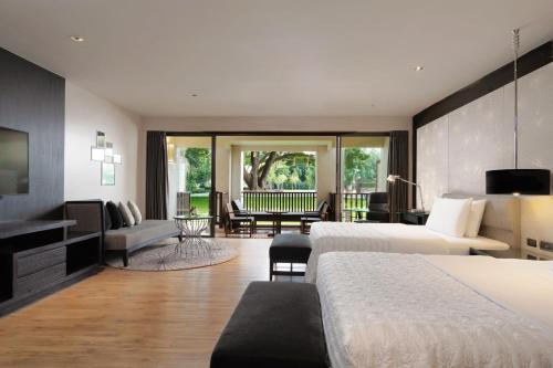 a hotel room with two beds and a living room at Le Meridien Chiang Rai Resort, Thailand in Chiang Rai