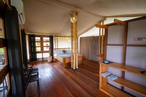 a room with a bed and a wooden floor at Houttuyn Wellness River Resort in Paramaribo