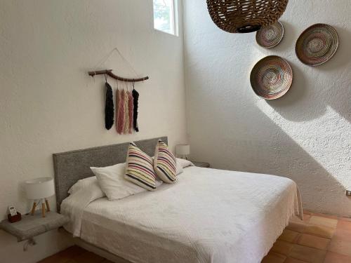 Schlafzimmer mit einem Bett mit weißer Bettwäsche und Kissen in der Unterkunft Casa Tabachin in Alpuyeca