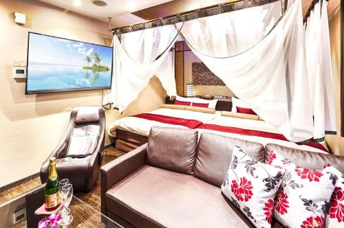 1 dormitorio con sofá, cama y TV en Hotel Bali An Resort Shinsaibashi, en Osaka