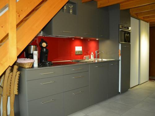 une cuisine avec des placards gris et un mur rouge dans l'établissement Appartement duplex familial 6 pers. à Crest-Voland avec balcon et à 50m des pistes - FR-1-733-67, à Crest-Voland