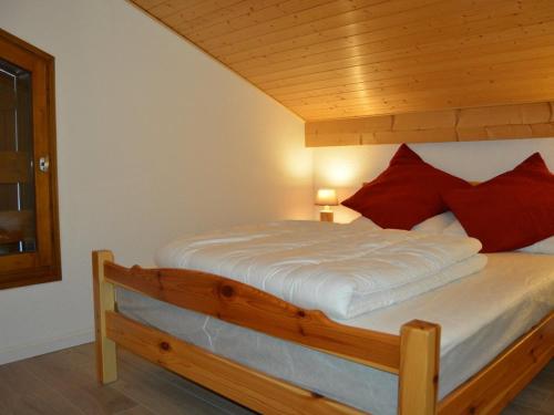 - un lit en bois avec des oreillers rouges dans l'établissement Appartement duplex familial 6 pers. à Crest-Voland avec balcon et à 50m des pistes - FR-1-733-67, à Crest-Voland