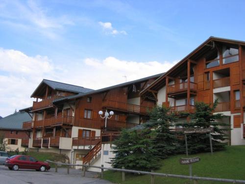 un bâtiment avec une voiture rouge garée devant lui dans l'établissement Appartement cosy 1 chambre, 4 pers, centre station, 100m des pistes, balcon, bien équipé - FR-1-733-107, à Crest-Voland