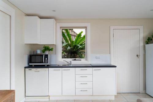 a white kitchen with a microwave and a window at Gull Cottage by Beach Stays in Church Point