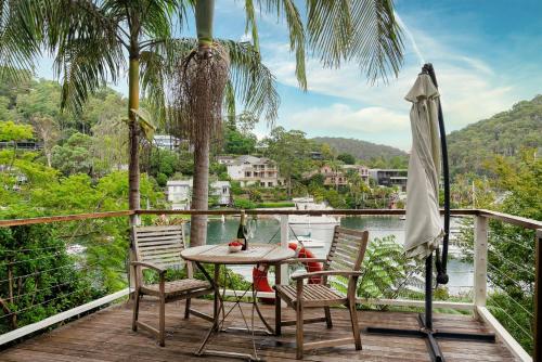 a table and chairs on a deck with a view of the water at Gull Cottage by Beach Stays in Church Point