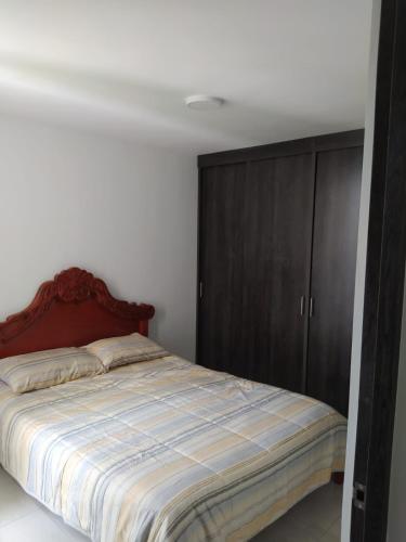 Apartahotel في إباغويه: غرفة نوم بسرير وخزانة خشبية
