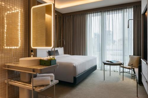 a bedroom with a bed and a sink and a mirror at Pan Pacific Orchard in Singapore