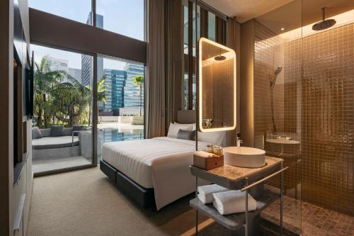 a bedroom with a bed and a bathroom with a sink at Pan Pacific Orchard in Singapore