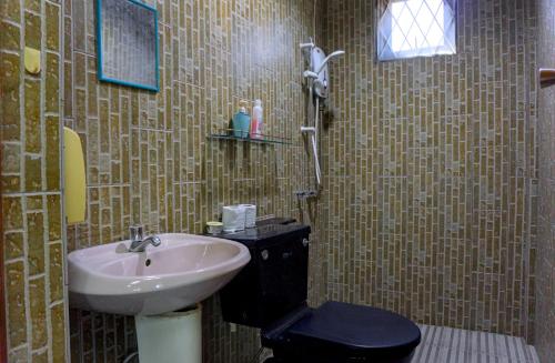 a bathroom with a sink and a toilet at Log Cabin House in Lutong