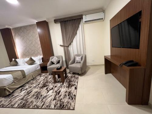 a hotel room with a bed and a flat screen tv at سمو سويت للشقق المخدومة 2 Smo Suites in Riyadh