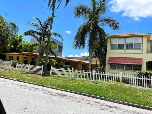 a white fence in front of a house with palm trees at CLR St. Pete in St Petersburg