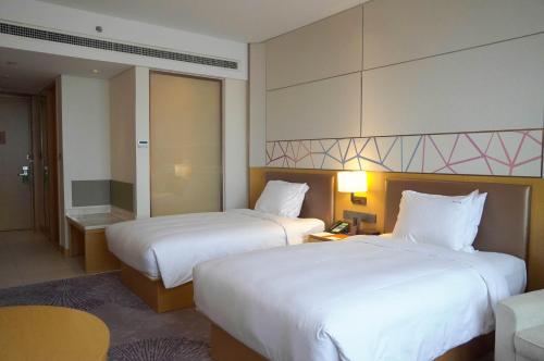 a hotel room with two beds and a table at Holiday Inn Tianjin Xiqing by IHG in Tianjin