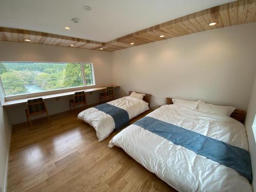 2 Betten in einem Schlafzimmer mit einem großen Fenster in der Unterkunft Ayu House - Vacation STAY 03971v in Nagahama