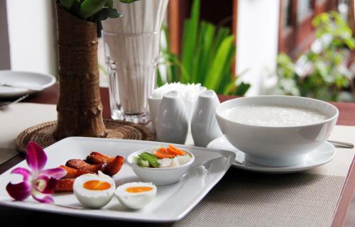 a plate with eggs and a bowl of soup on a table at Cambana d'Angkor Suites in Siem Reap