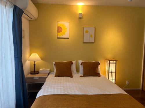 a bedroom with a bed with a yellow wall at 镰仓、藤沢冲浪胜地 近新江之岛水族馆 距离沙滩1分钟 整套公寓 in Fujisawa