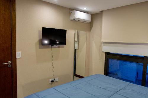 una camera da letto con un letto e una TV a parete di Depto nuevo 1 Dormitorio Excelente Ubicación a Mendoza