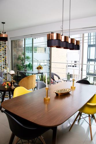 a dining room with a wooden table and yellow chairs at D HABITACION MANDALA NEBRASKA 63 in Mexico City