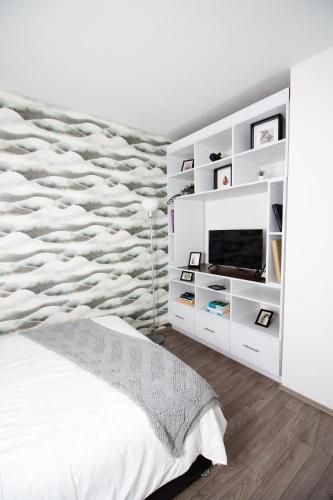 a white bedroom with a bed and a tv at D HABITACION MANDALA NEBRASKA 63 in Mexico City