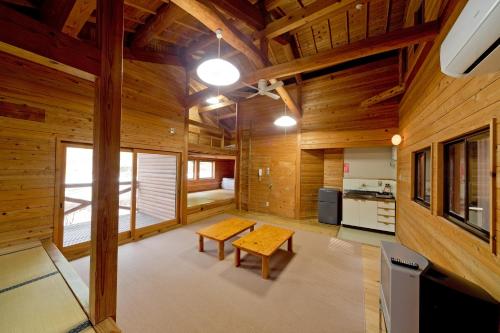 a living room with wooden walls and a wooden table at Hiyoshi Forest Resort Yamanoie in Nantan city