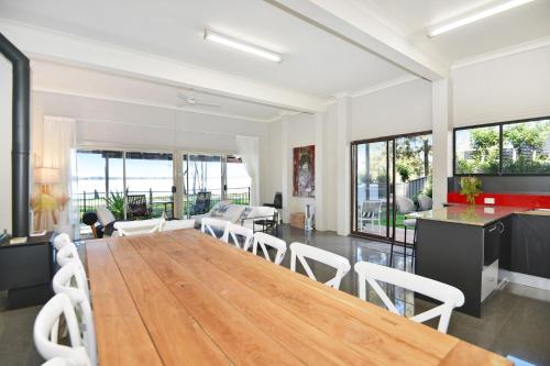a dining room and living room with a wooden table and chairs at Parkway Lakehouse in Budgewoi