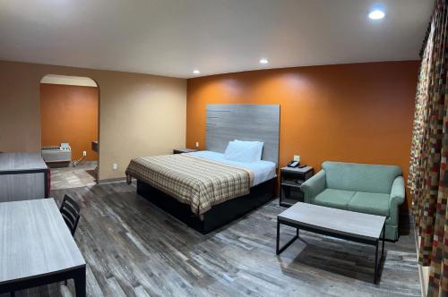 um quarto de hotel com uma cama e uma cadeira em Apex Inn em Modesto
