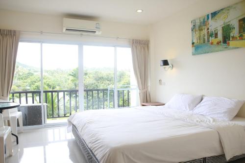 1 dormitorio con 1 cama grande y balcón en Choengmon Residence, en Choeng Mon Beach