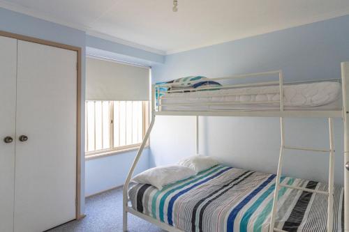 a bedroom with two bunk beds and a window at Peaceful Cul de sac in Sussex Inlet