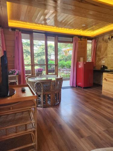 a living room with a table and some windows at The Chalets Naldehra in Shimla