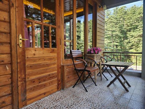 a patio with a table and chairs on a porch at The Chalets Naldehra in Shimla