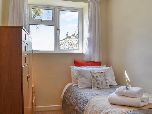 1 dormitorio con cama con almohadas y ventana en Thornes Farm Annexe, en West Quantoxhead